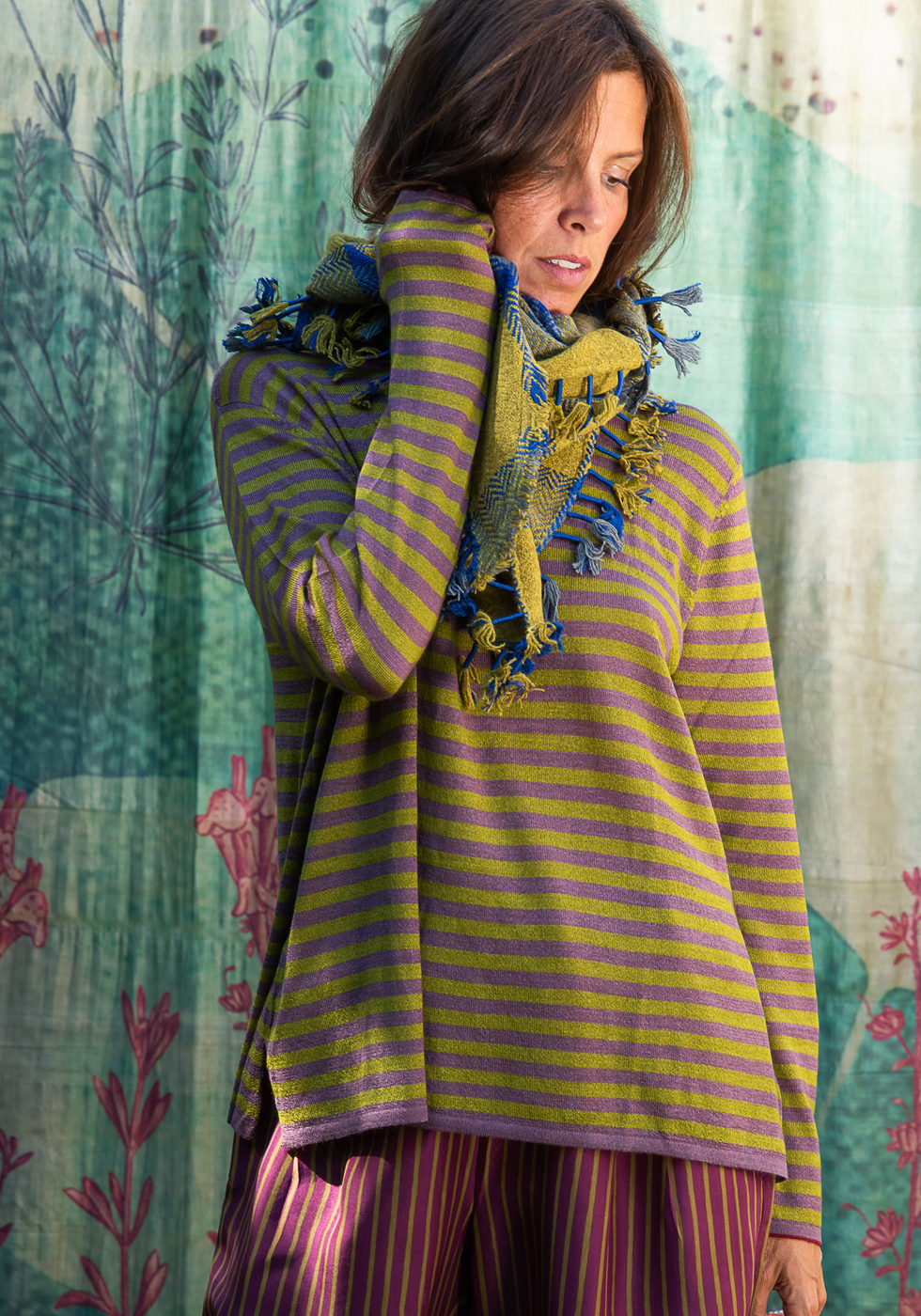 Green and purple striped tunic over a pleated skirt against the blue backdrop.