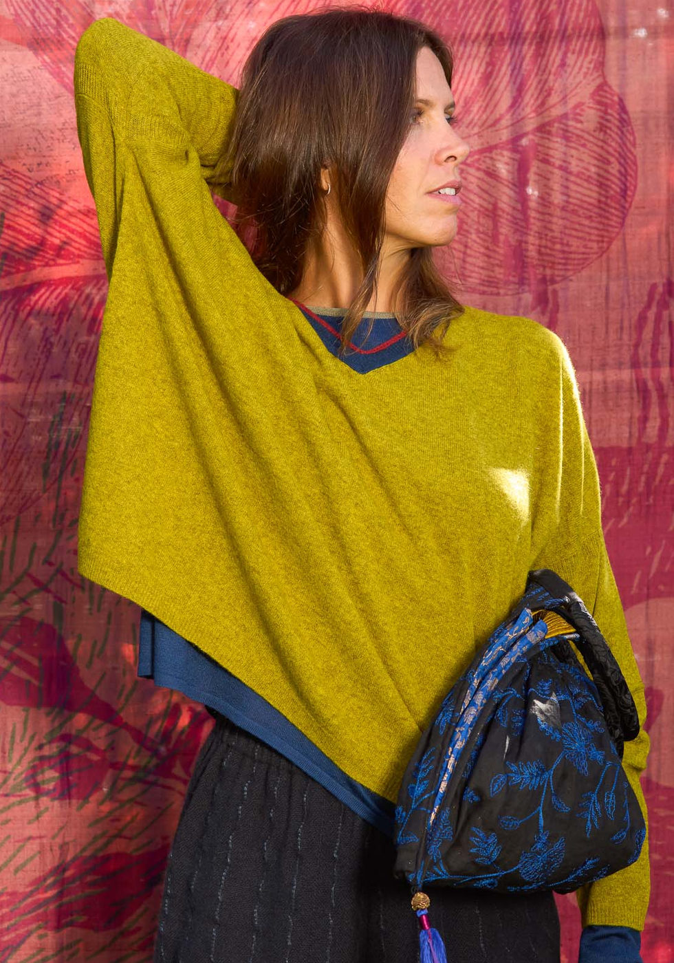 Yellow-green jumper with a blue bag against the red backdrop.