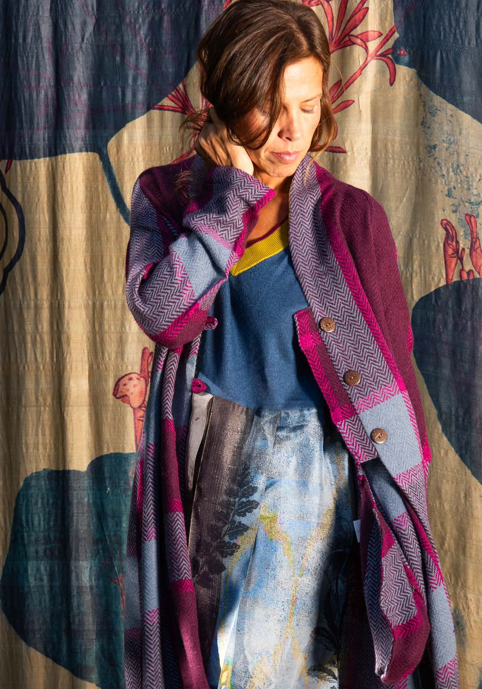 Purple and magenta cardigan over a printed outfit against the dark blue botanical backdrop.