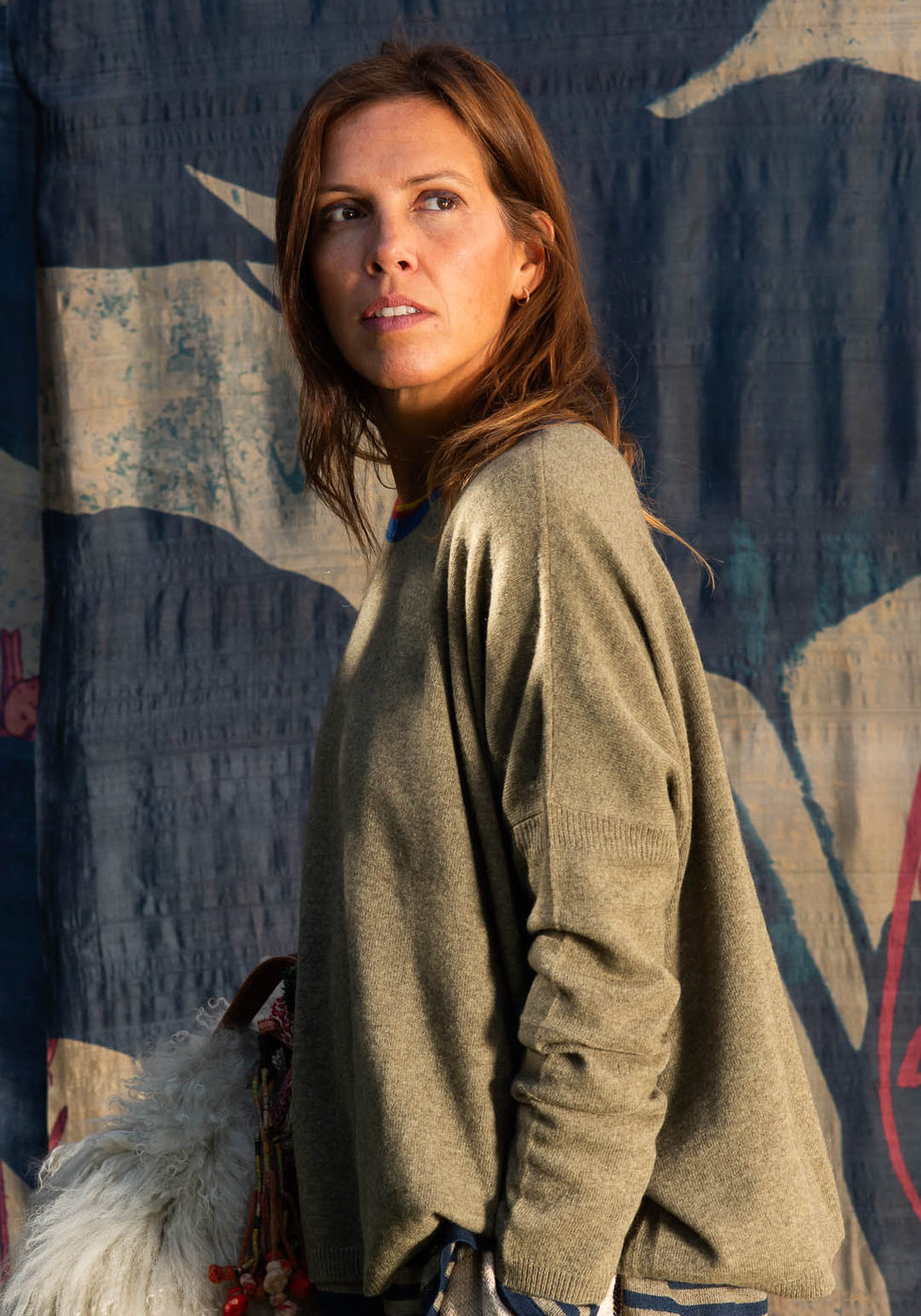 Olive green coat with light striped trousers against the dark blue botanical backdrop.