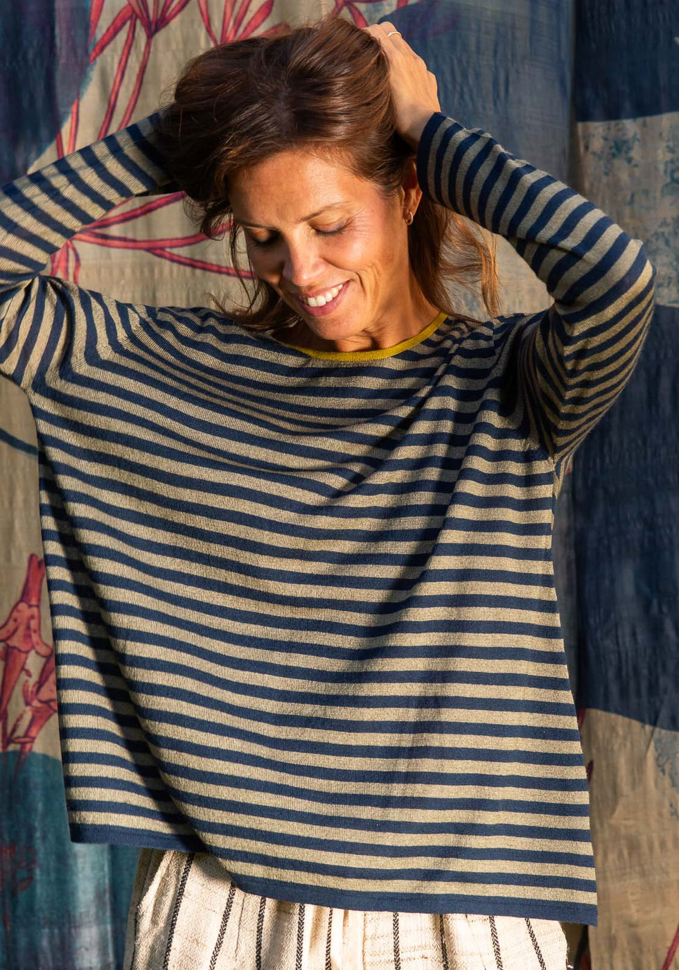 Dark and light striped jumper with light trousers against the dark blue botanical backdrop.